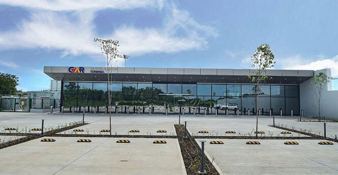 Modern cargo terminal building with glass facade and parked vehicles in front
