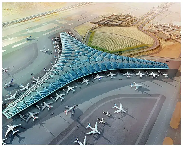 Aerial view of a futuristic airport terminal with a wing-like design, surrounded by aircraft on the tarmac and expansive desert landscape