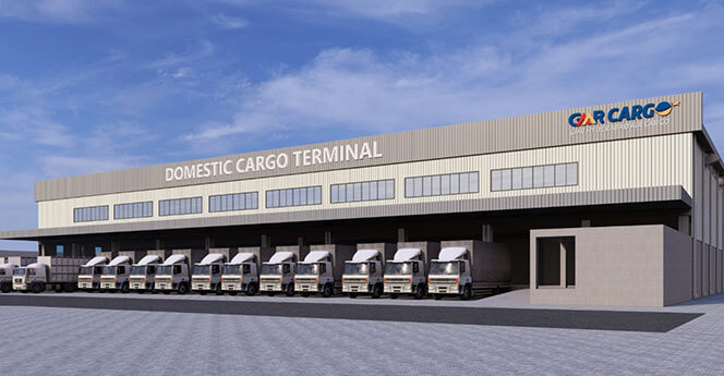 Domestic Cargo Terminal building with multiple trucks parked at loading docks and company logo on the facade.